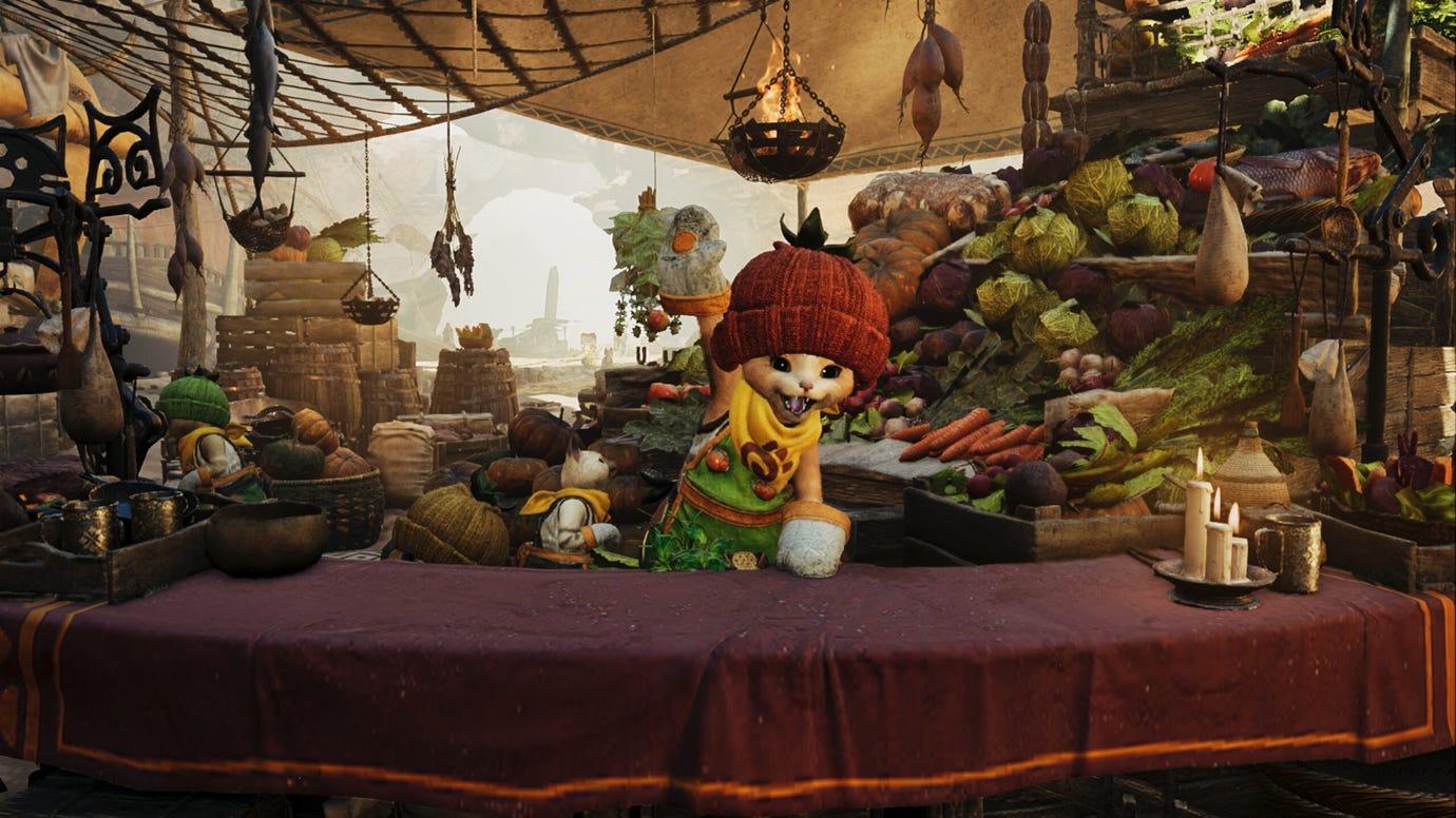A Monster Hunter Wilds screenshot of a Palico happily waving their hand from behind a table with a purple cloth and a bunch of vegetables behind it.