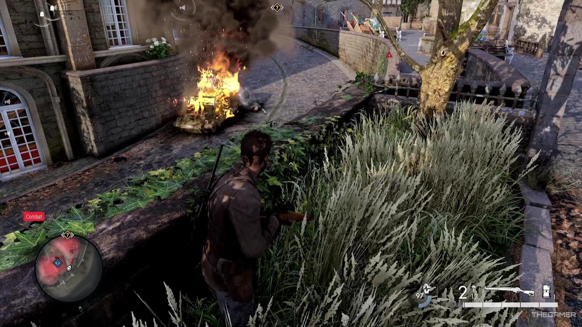 A flaming vehicle carcass sits burning on the road in Sniper Elite Resistance.