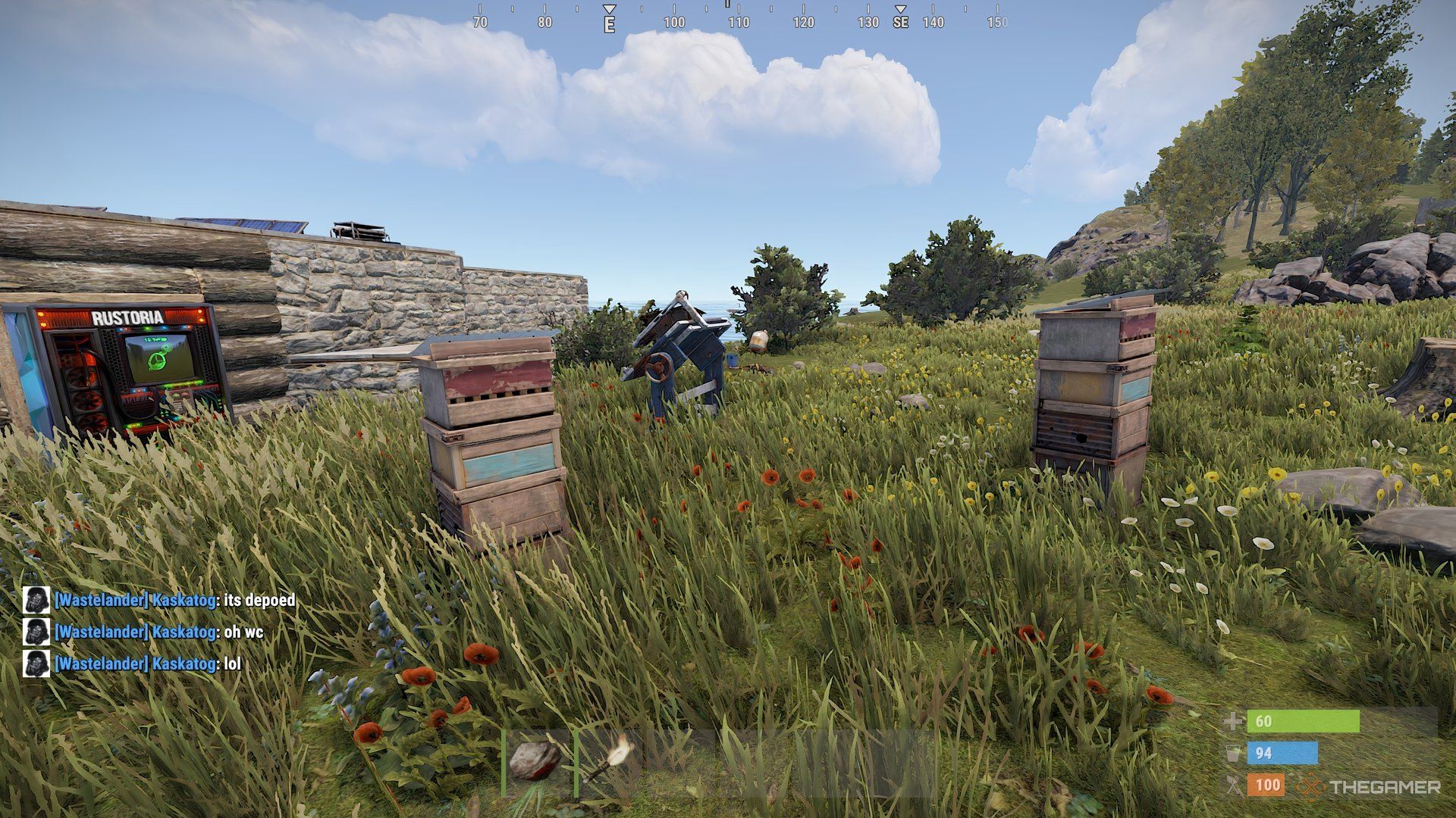Rust Beehive player looking a two beehives with a store a the background. 