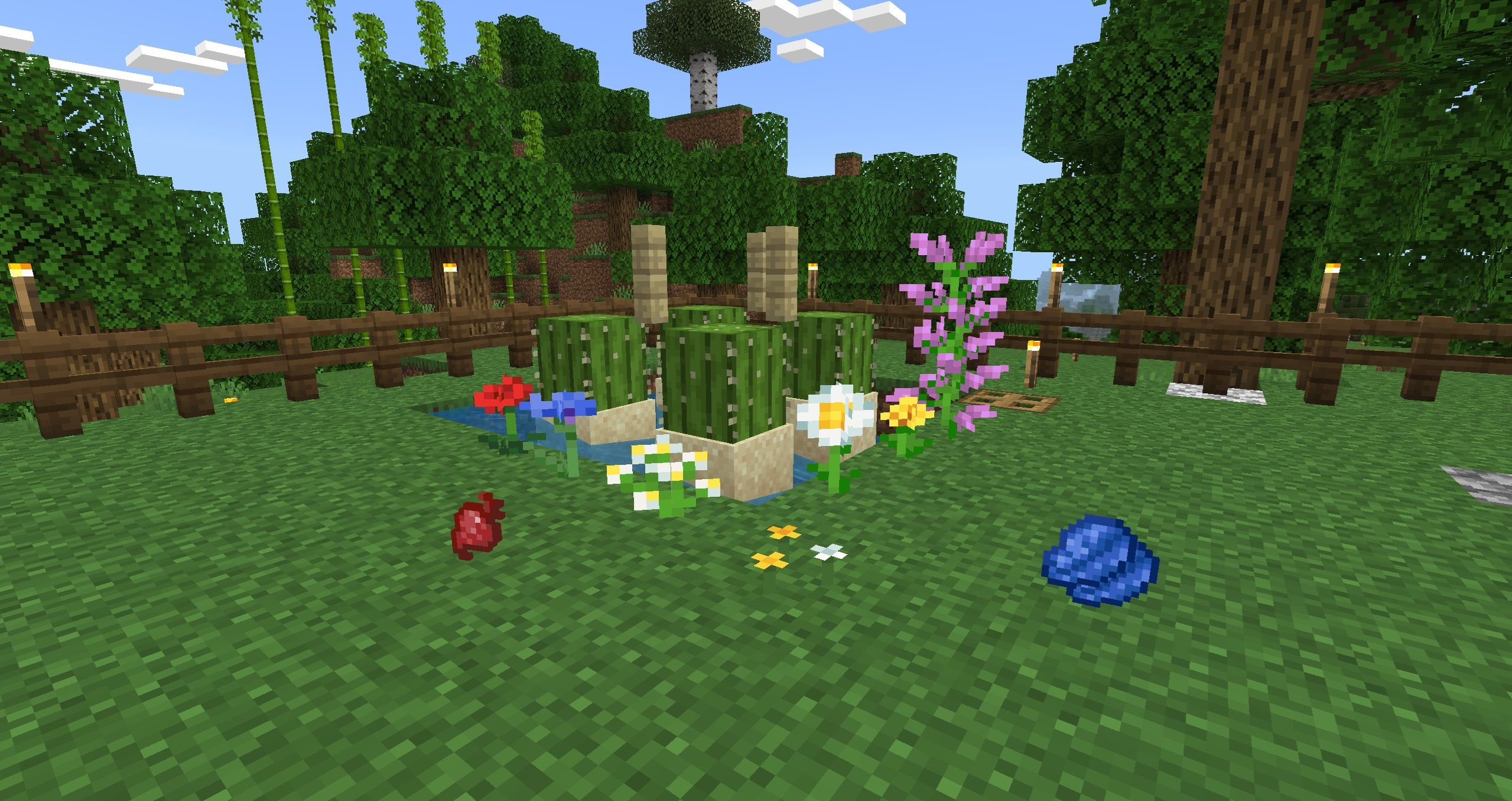 A bunch of common dye ingredients laid out around an automatic cactus farm, which include flowers, lapis lazuli, and a beet, as well as the cactuses themselves in Minecraft.