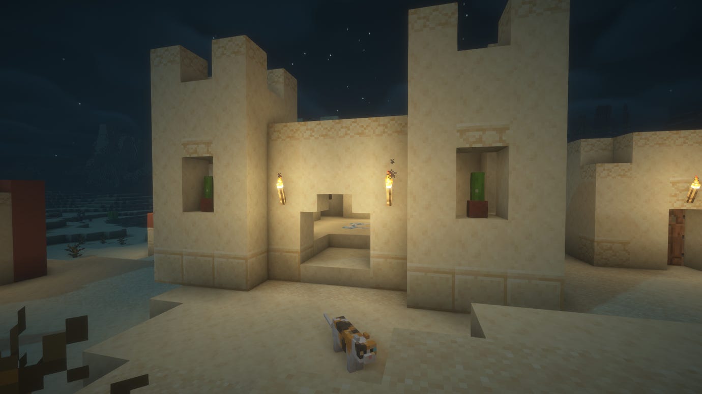 Screenshot of a desert village at night in Minecraft.