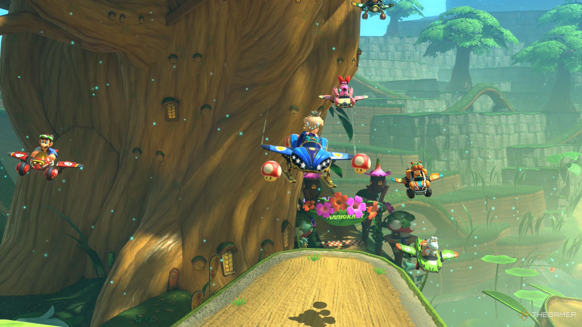 Luigi, Birdo, Rosalina, Daisy, and Yoshi gliding across a large gap, onto a spiraling tree trunk pathway in Mario Mark World.