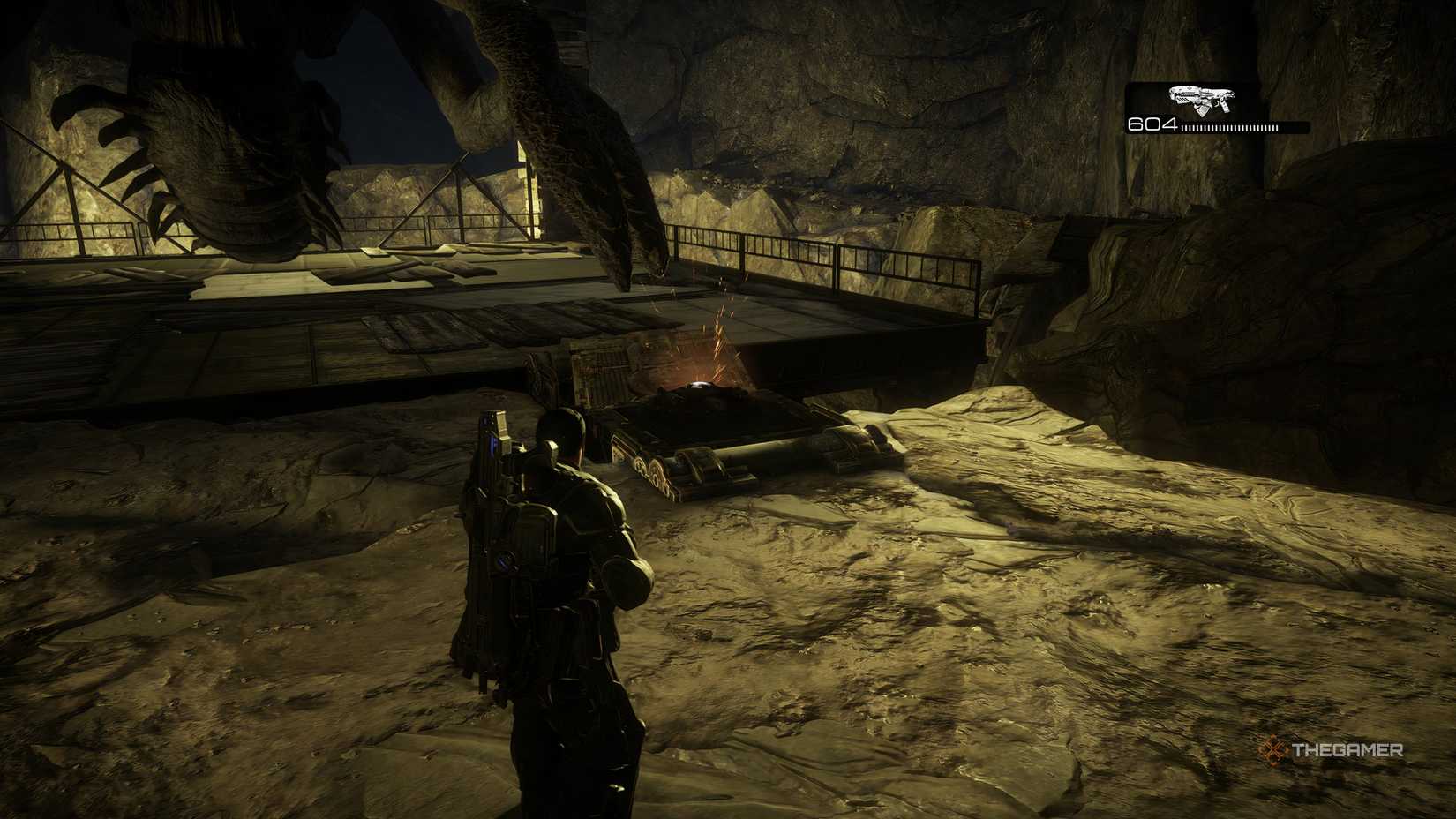 The player looking at a broken clamp with the Corpser standing on the platform ahead of them in Gears of War: Reloaded.