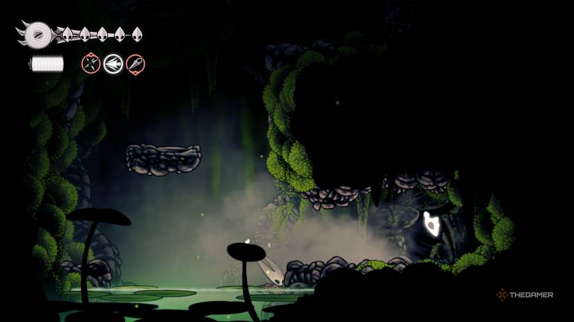 Hornet discovers the Mosslands Mask Fragment beneath the Wormway door in Hollow Knight: Silksong.