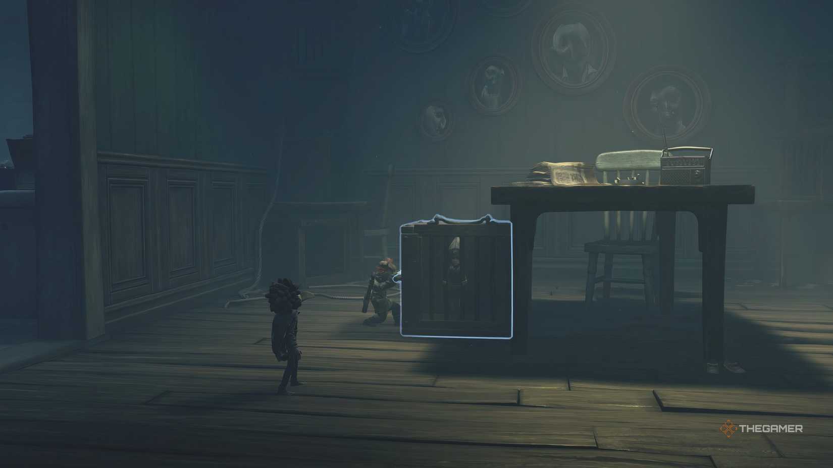 Alone pulling a cage from under a table in Little Nightmares 3.